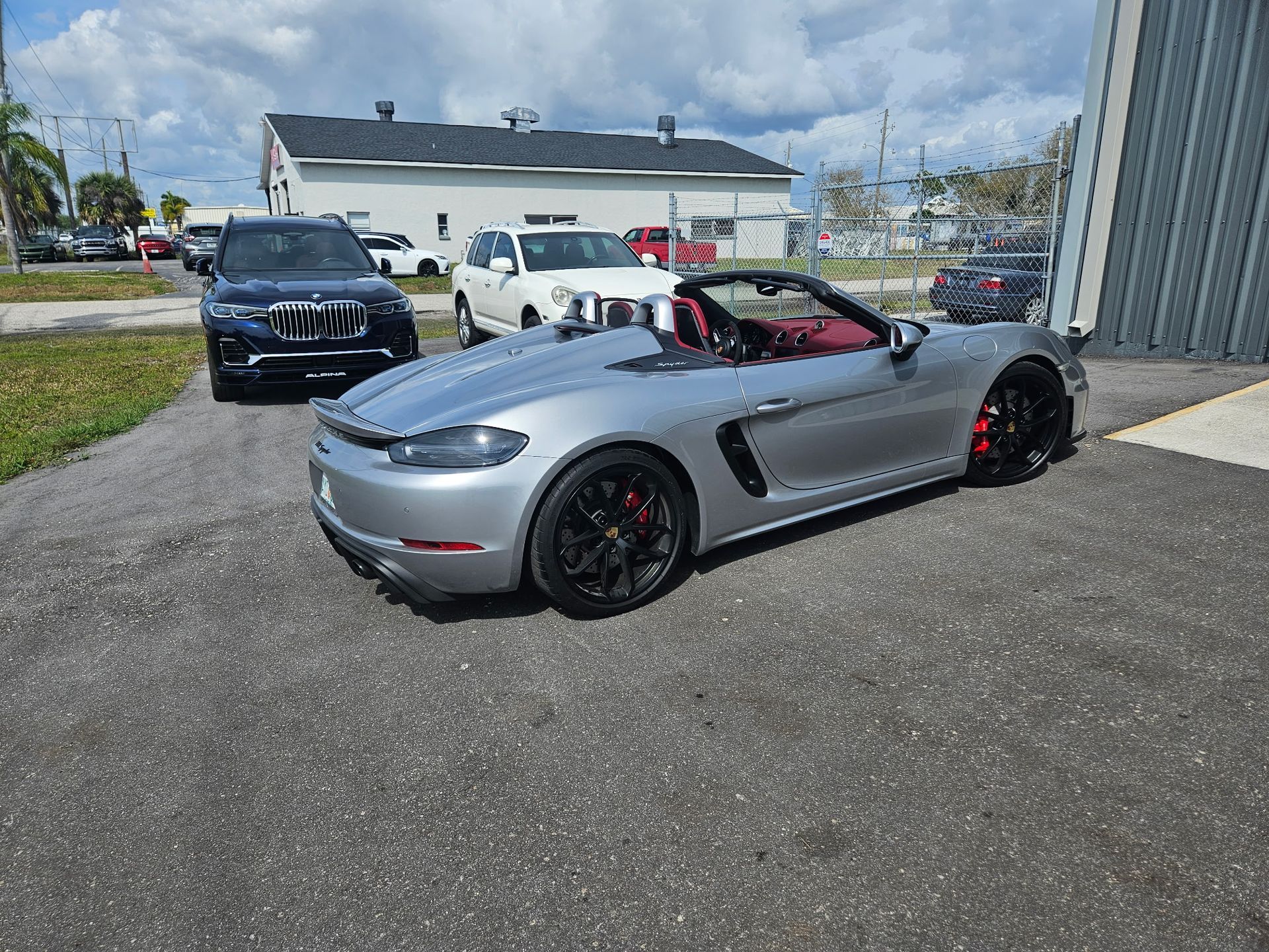 A silver sports car is parked in a parking lot next to a building.