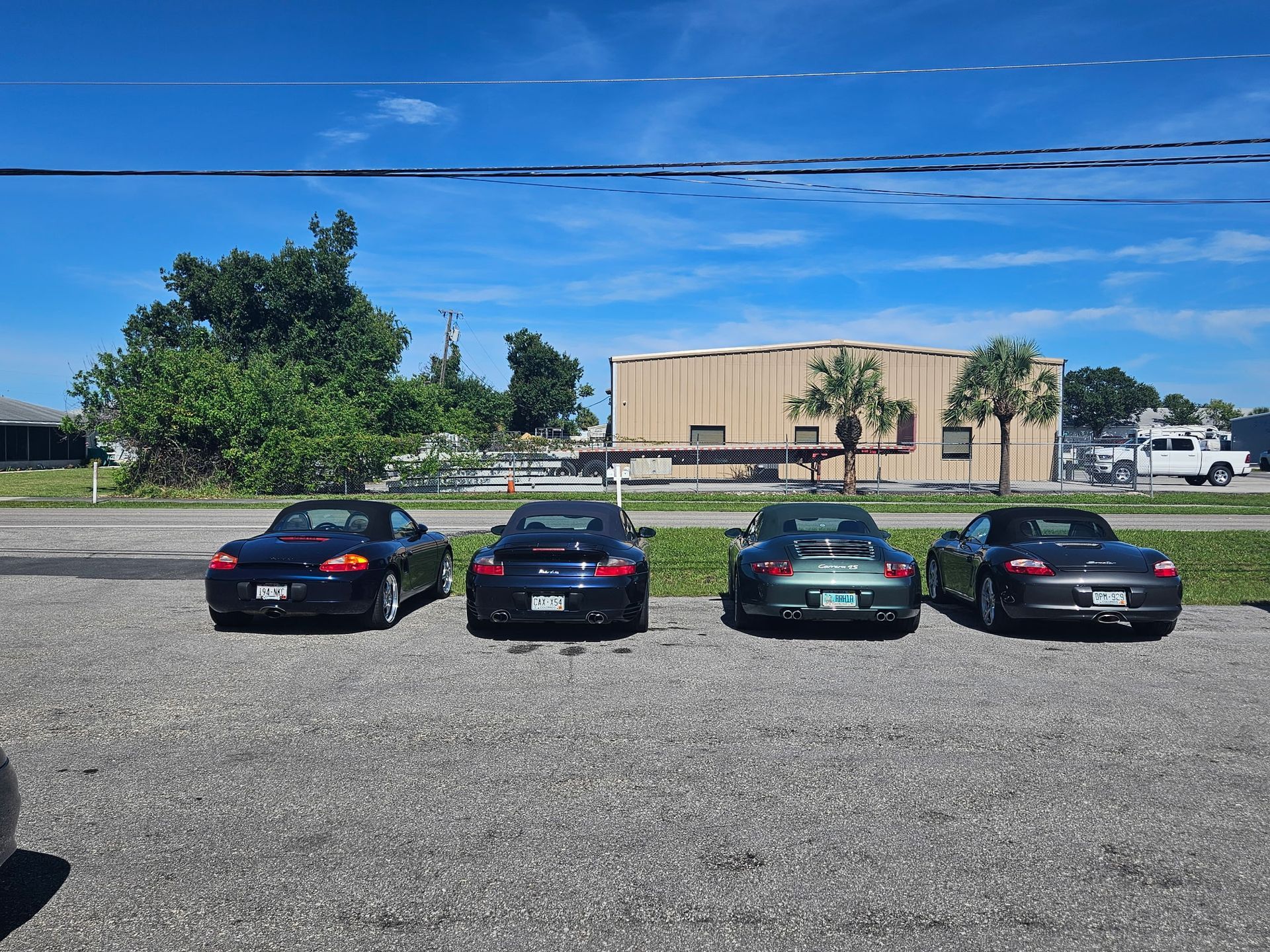 A row of cars are parked in a parking lot in front of a building.