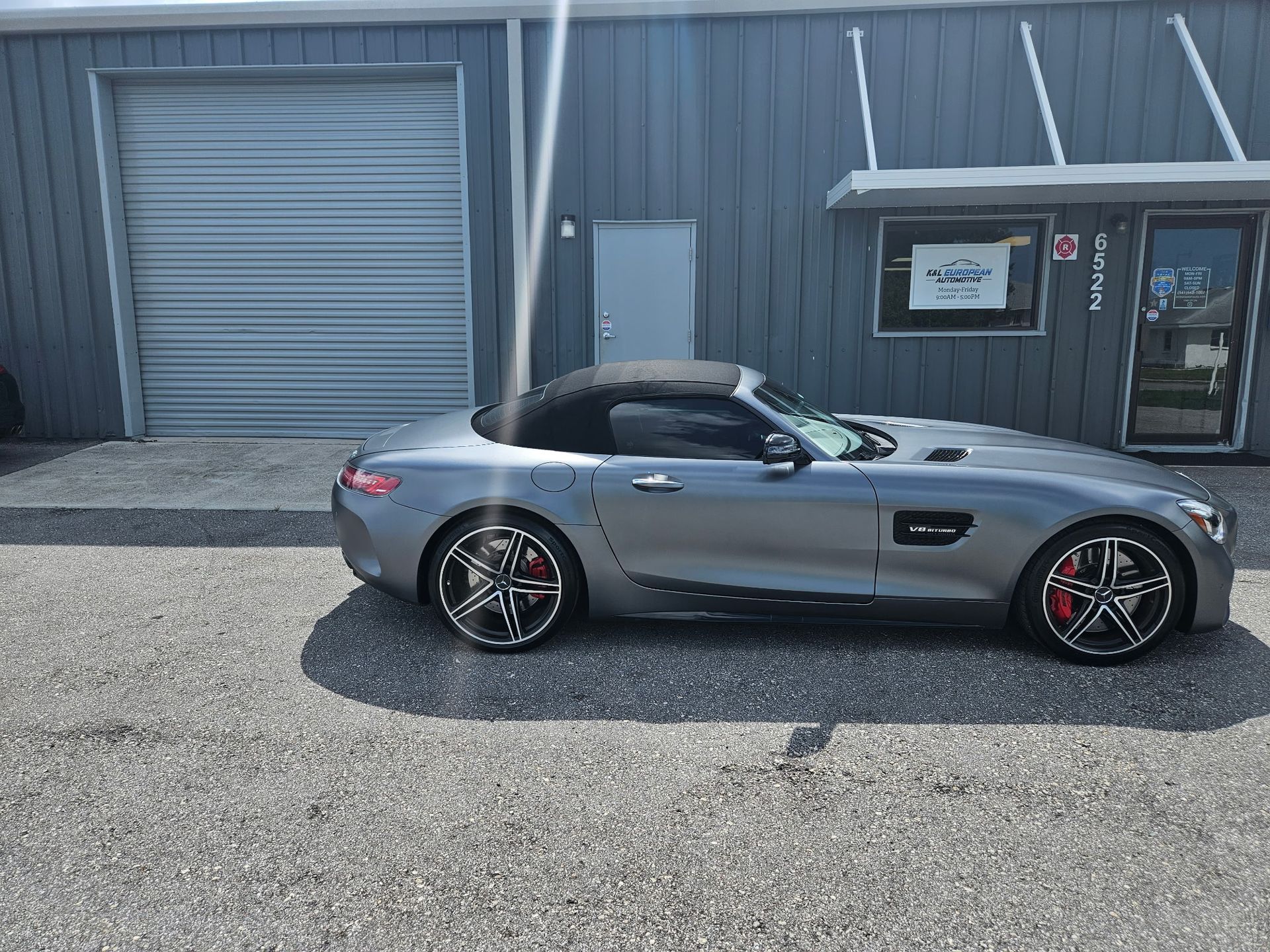 A mercedes amg gt convertible is parked in front of a building.