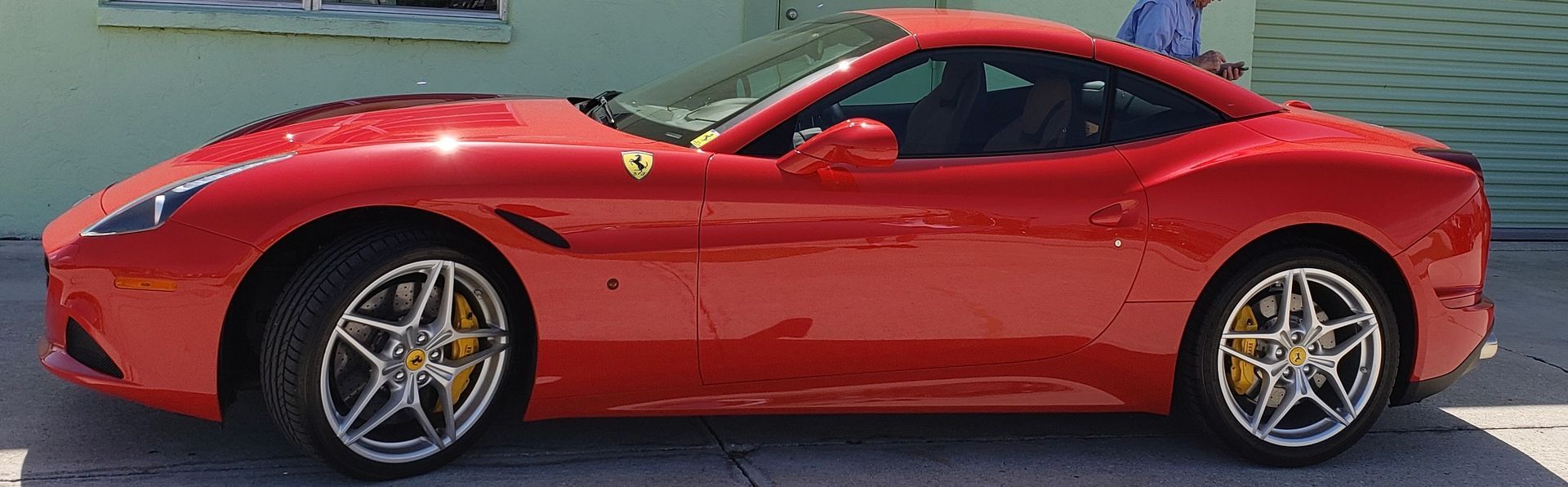 A red ferrari is parked on the side of the road