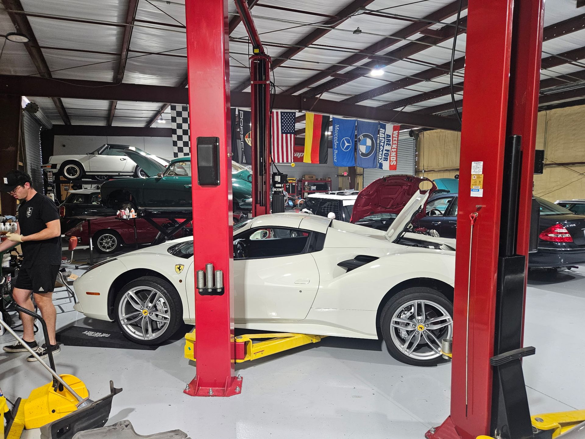 A white sports car is on a lift in a garage.