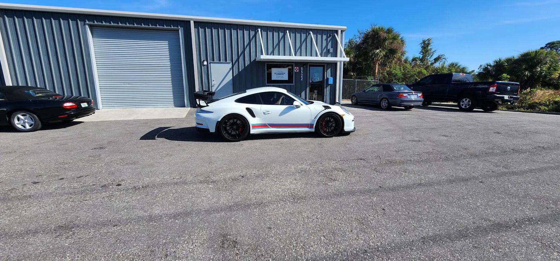 A white sports car is parked in a parking lot in front of a building.