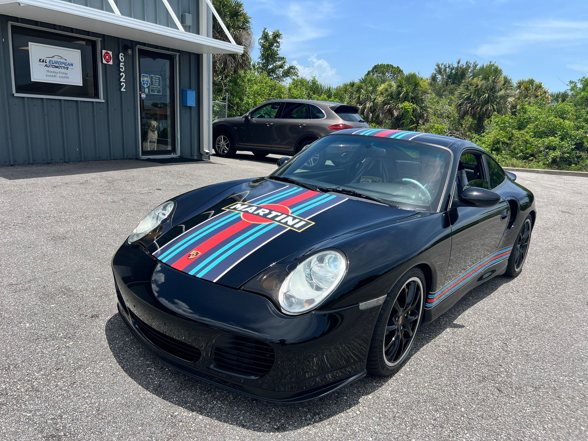 A black porsche 911 turbo is parked in front of a building.