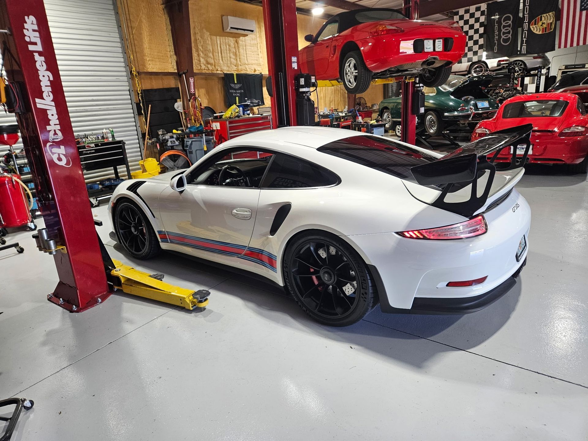 A white porsche is parked on a lift in a garage.