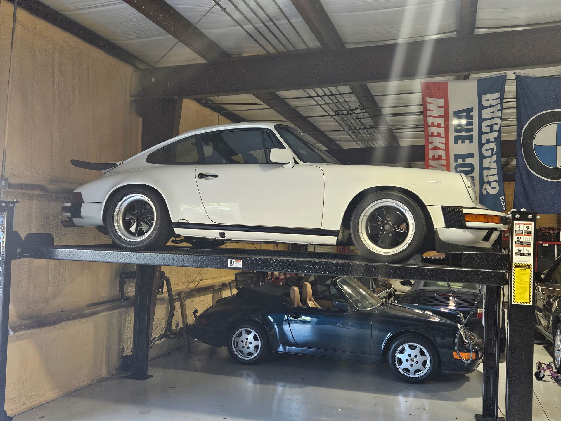 A white porsche is parked on a lift in a garage