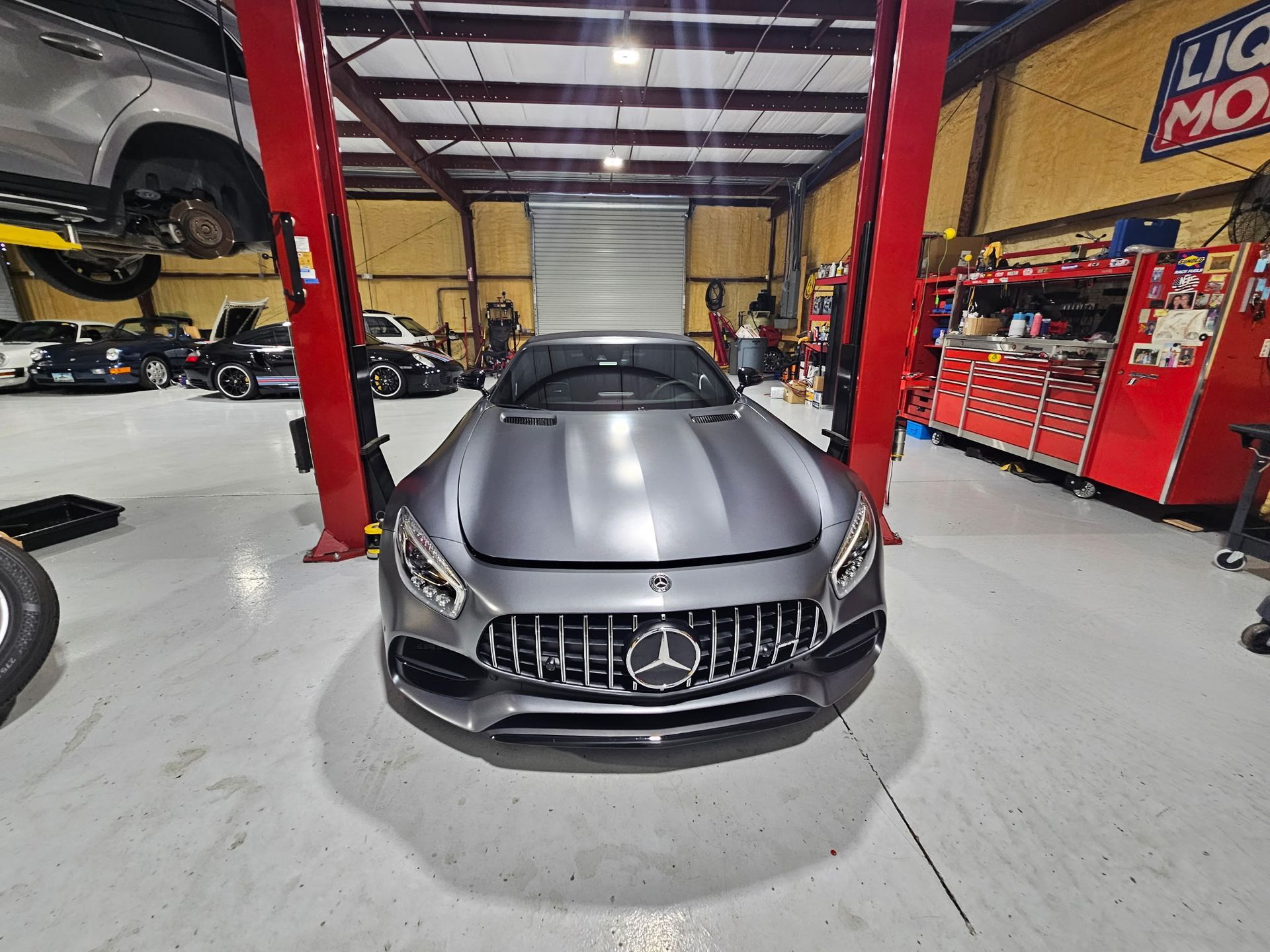 A mercedes benz is sitting on a lift in a garage.