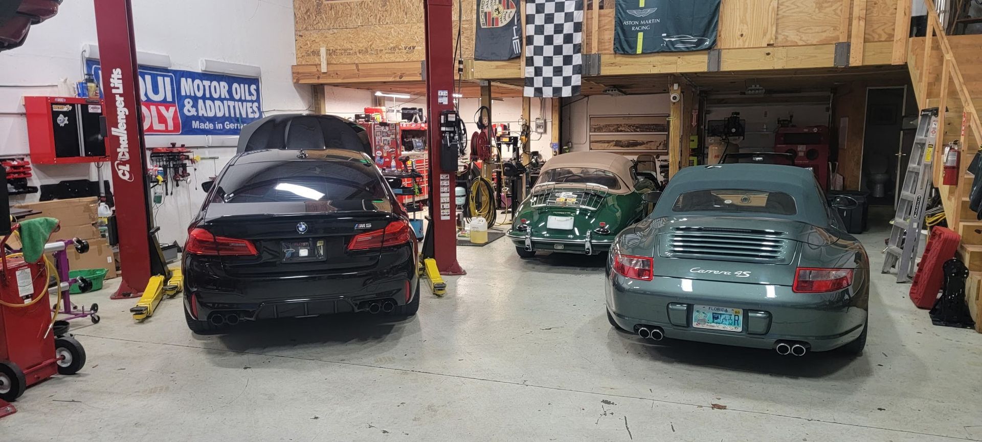 A couple of cars are parked in a garage.