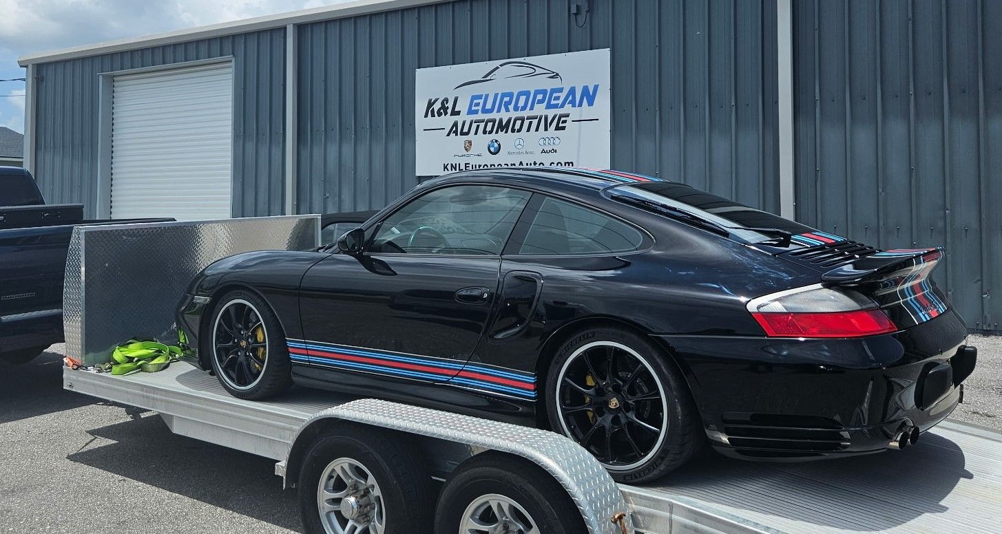A black sports car is on a trailer in front of a building.