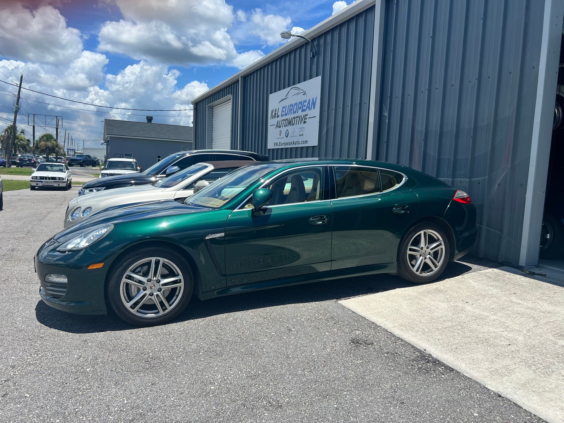 A green porsche panamera is parked in front of a building.