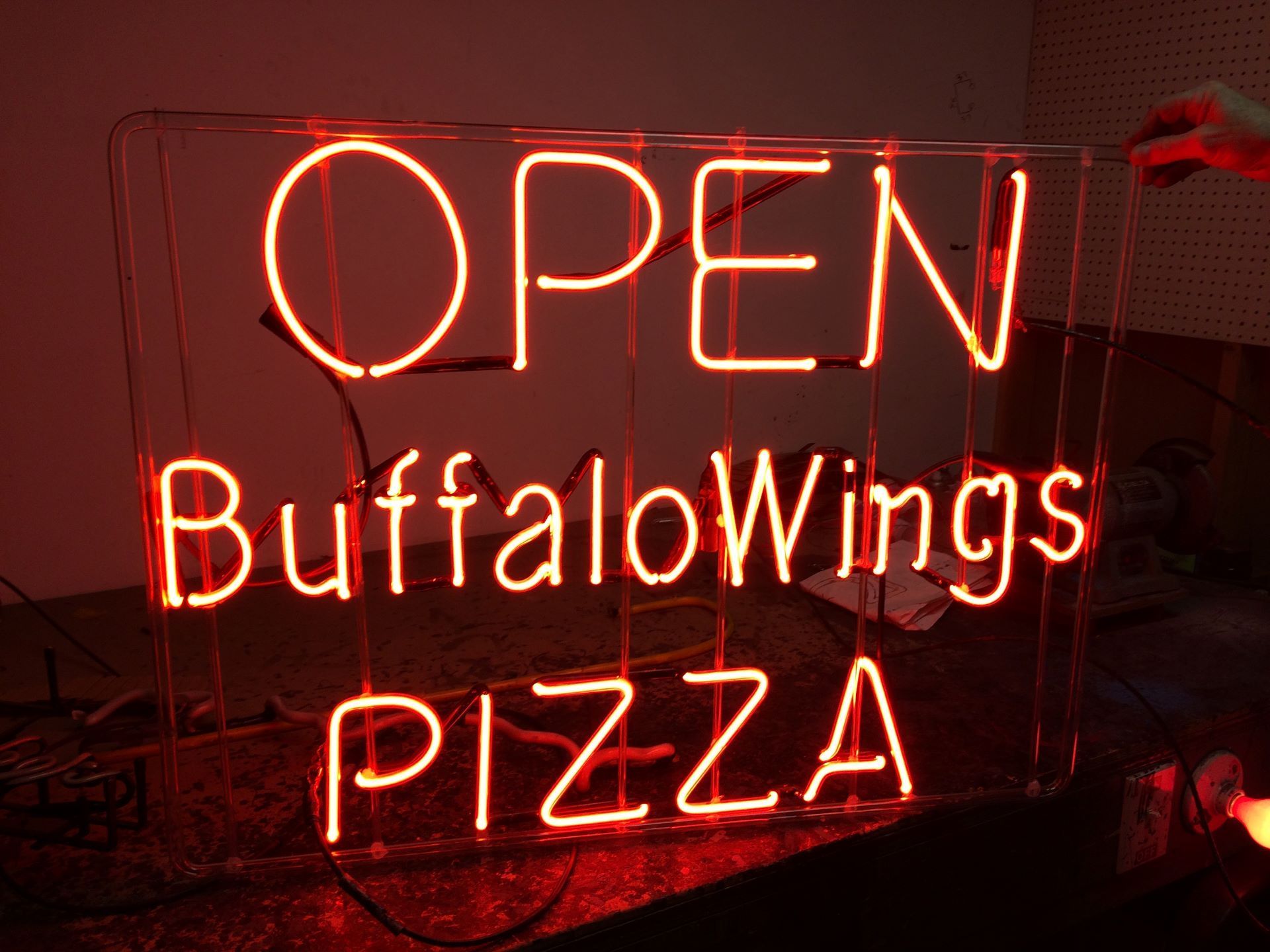 A neon sign that says open buffalo wings pizza