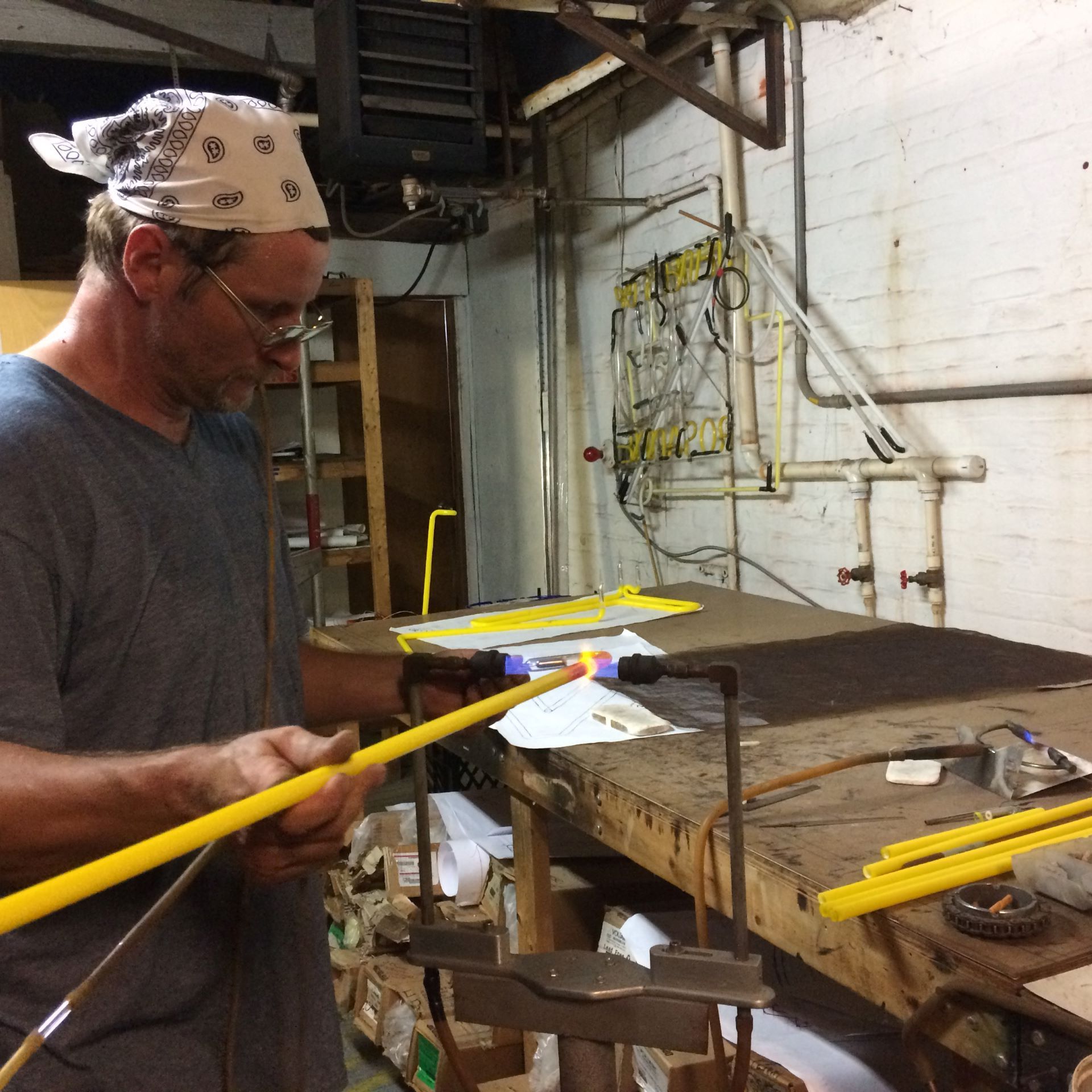A man wearing a bandana is holding a yellow pipe
