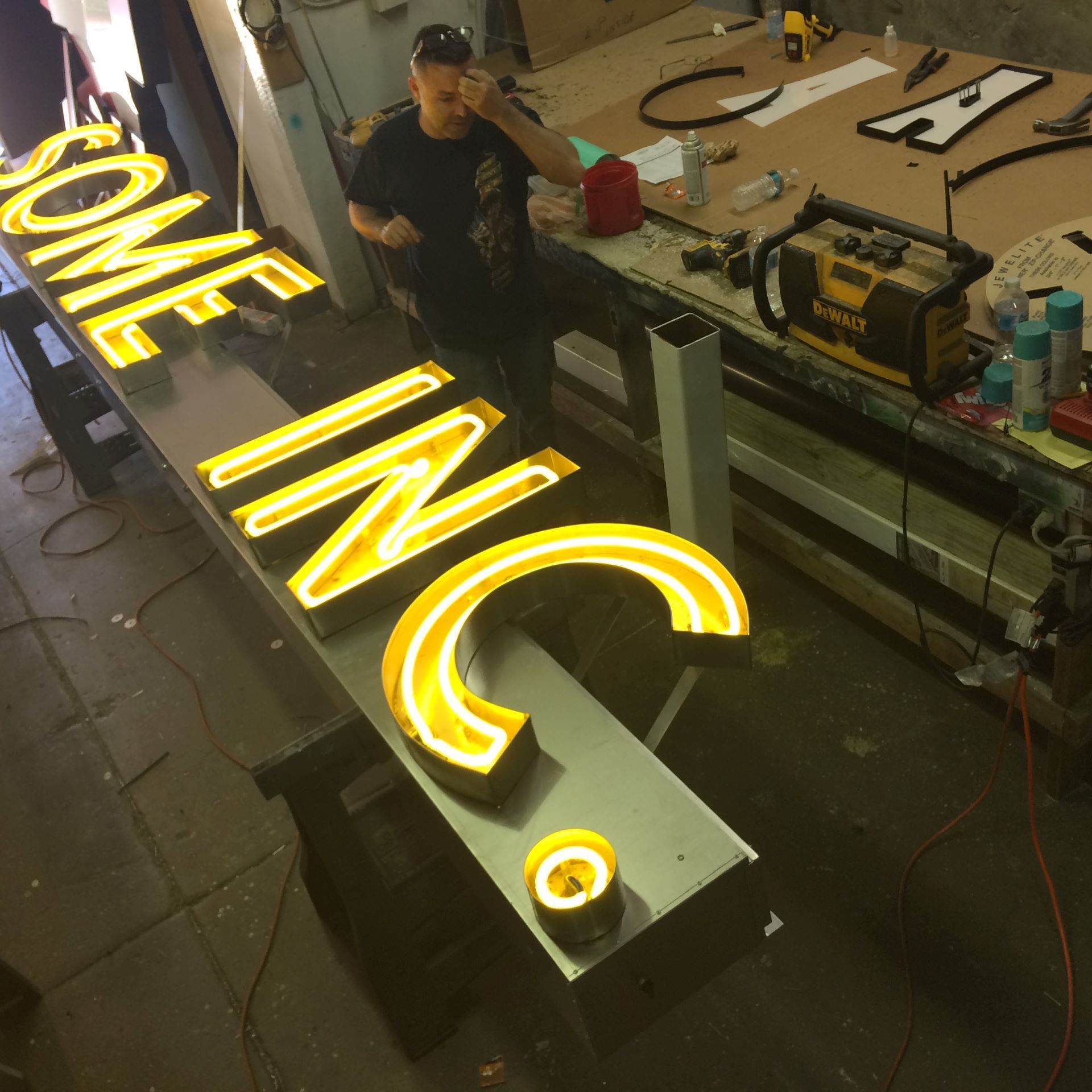 A man is working on a sign that says some inc.