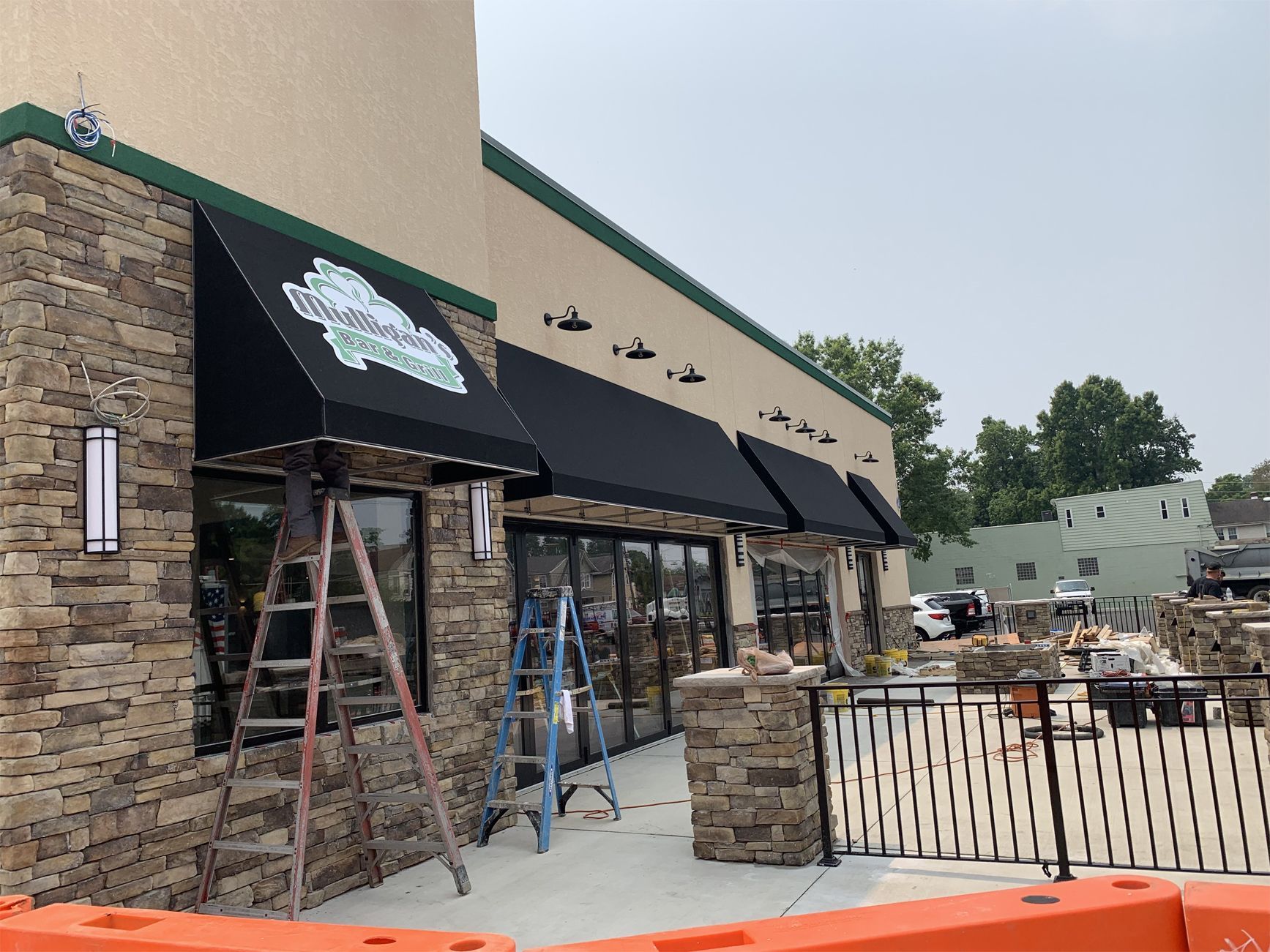 A black awning is being installed on the side of a building.