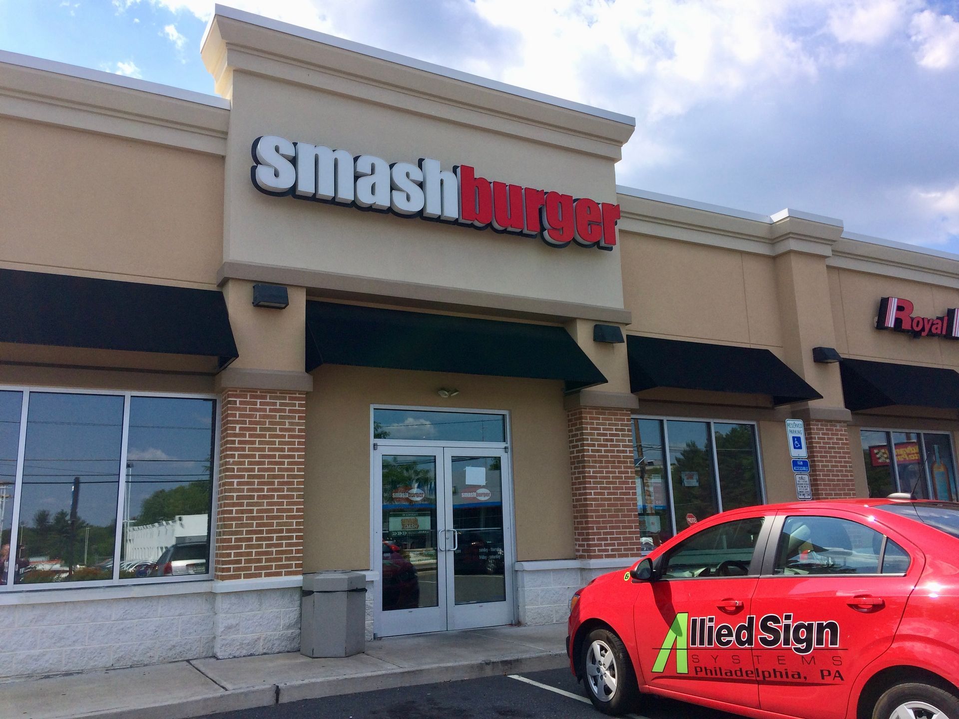 A red car is parked in front of a smashburger restaurant