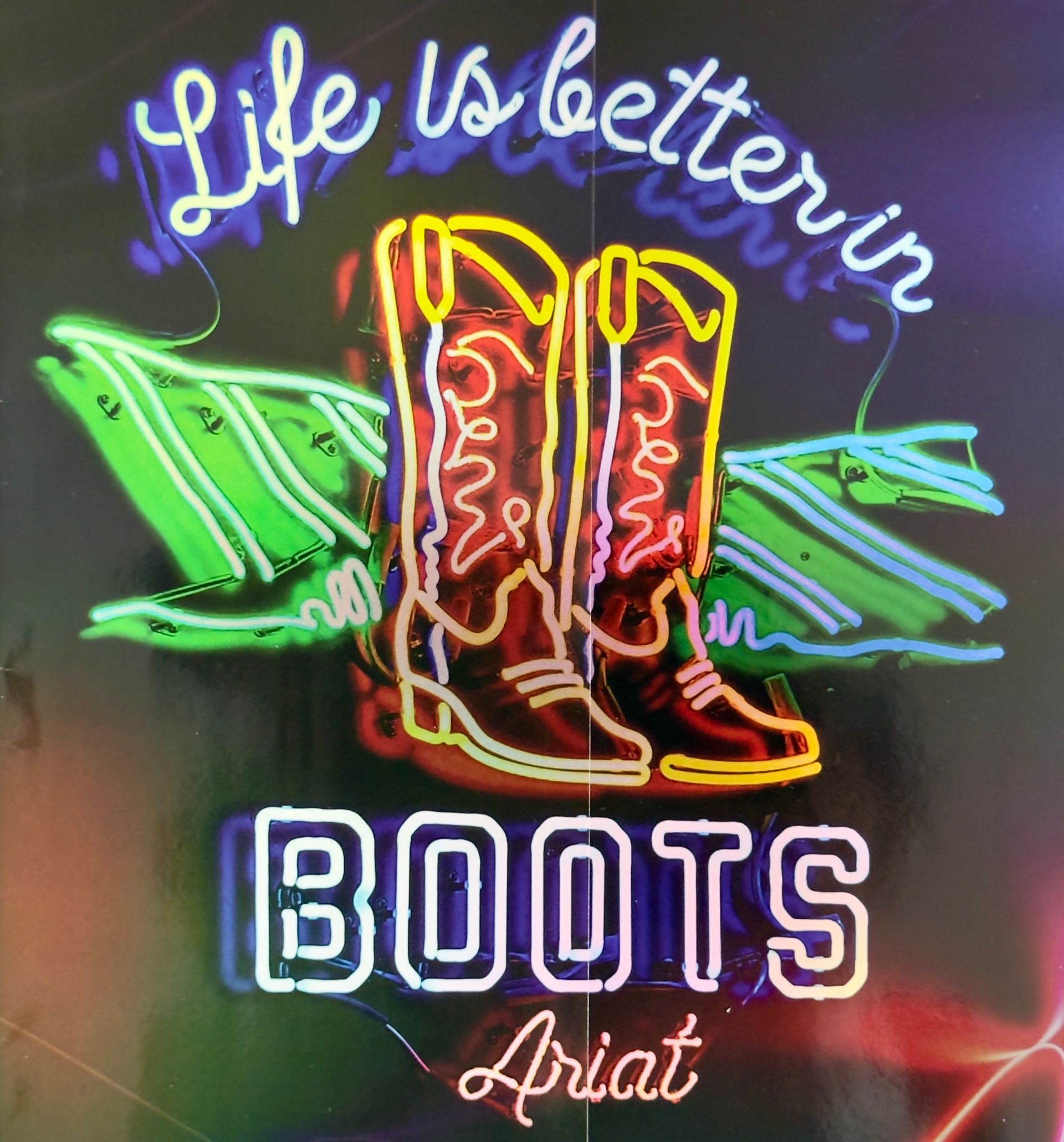 A neon sign that says life is better in boots
