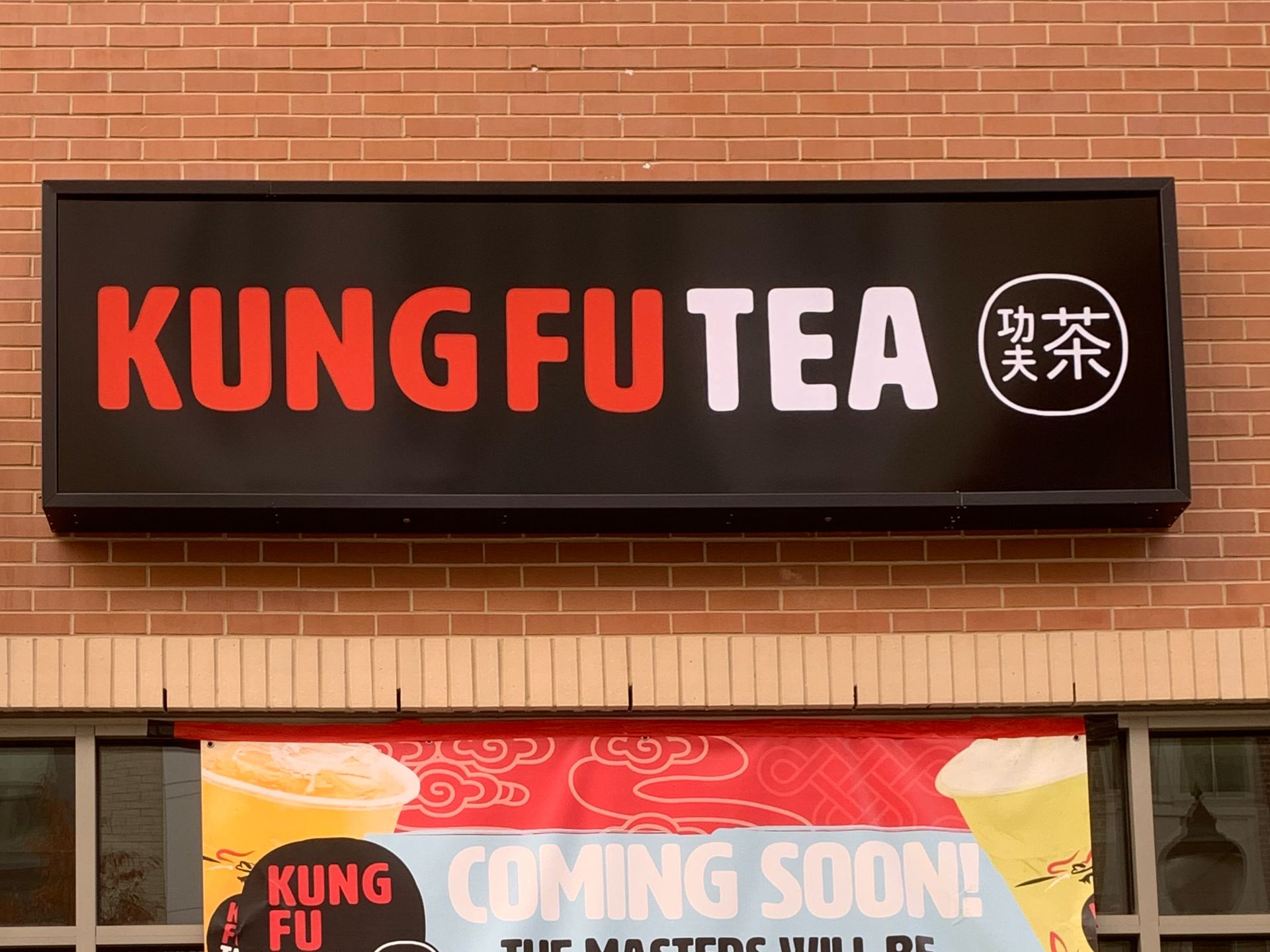 A box sign Kung Fu Tea hangs on a brick building