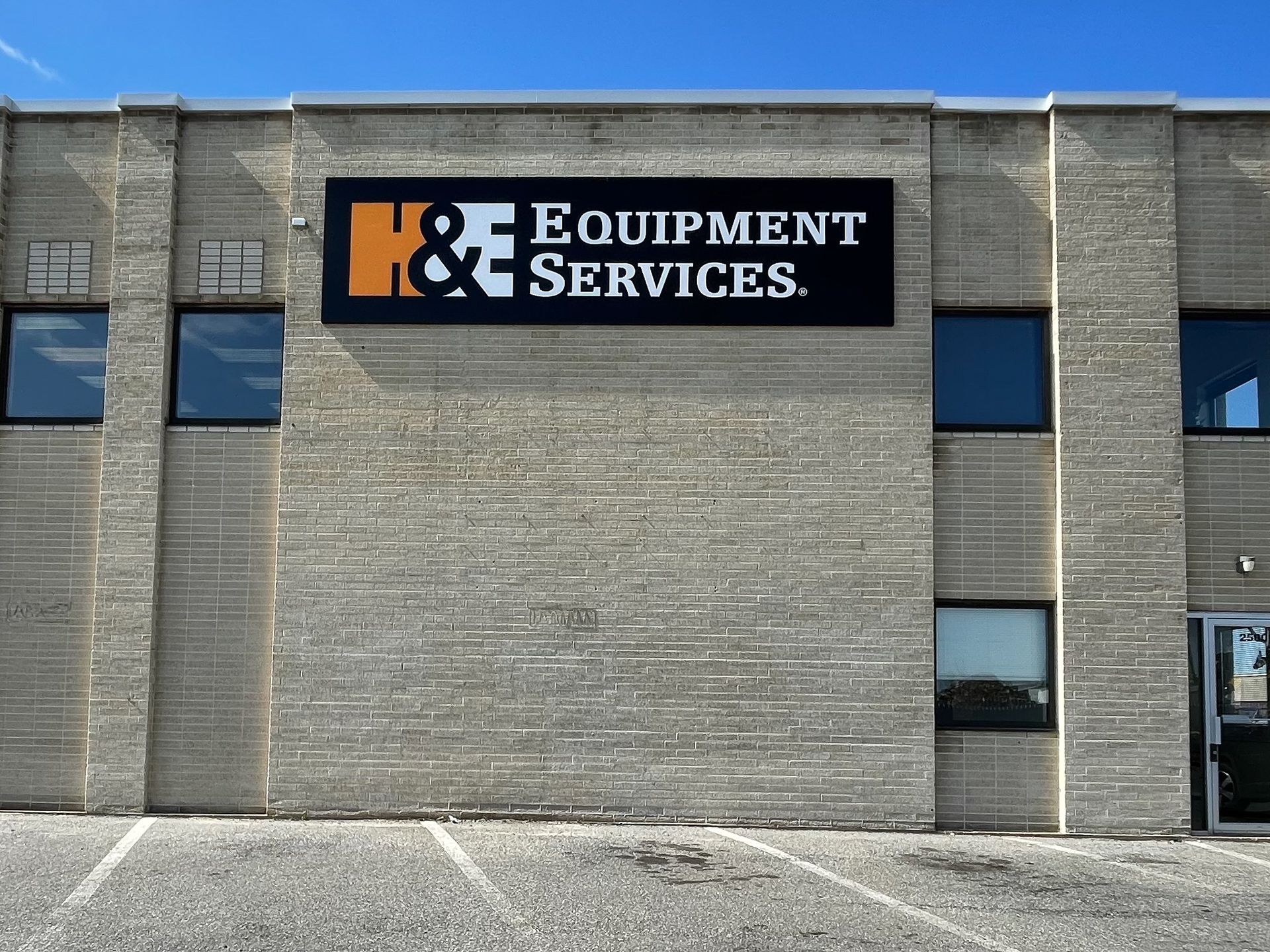 A brick building with a box sign that says H & E Equipment Services