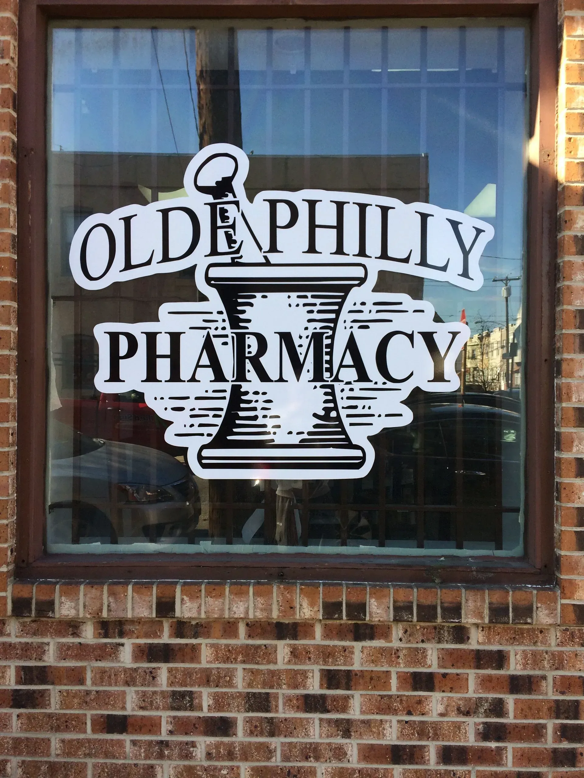 A brick building with a window that says olde philly pharmacy on it.