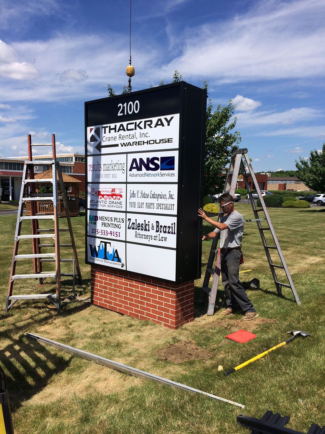 A man is installing a large free-standing sign.