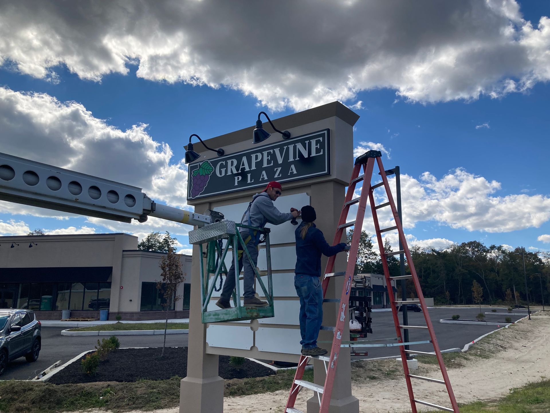 Two men are working on a sign for grapevine plaza.