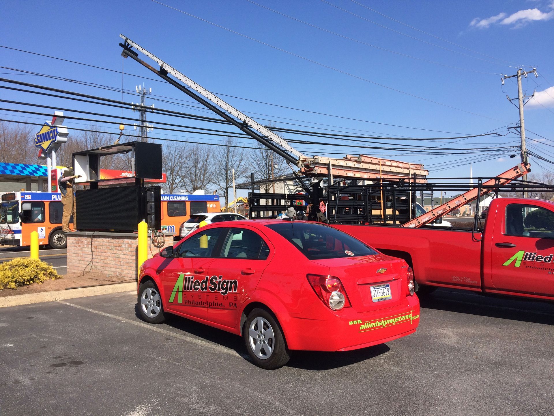 A red car is parked in a parking lot next to a red truck.