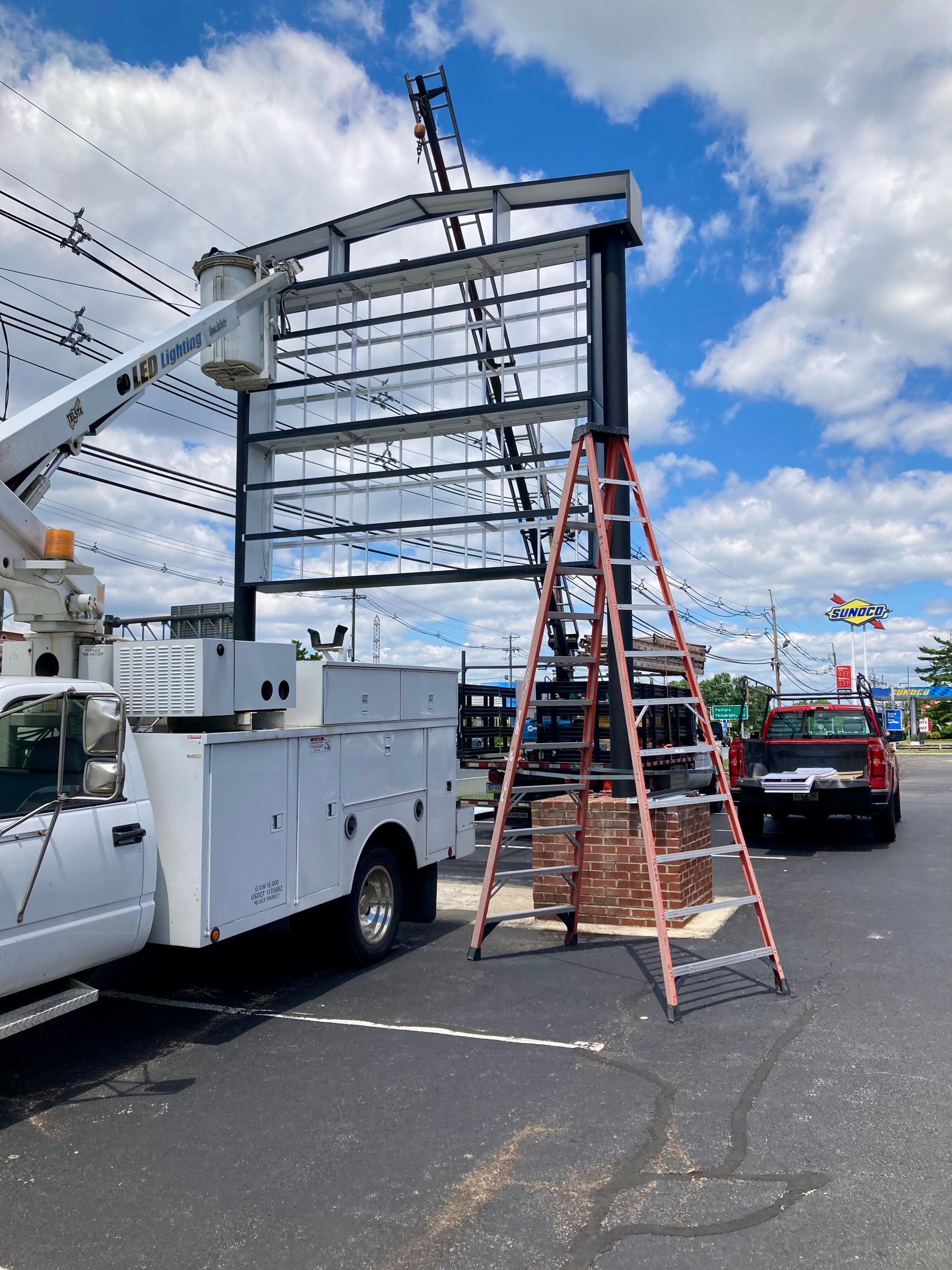 A white truck is parked in a parking lot next to a ladder.