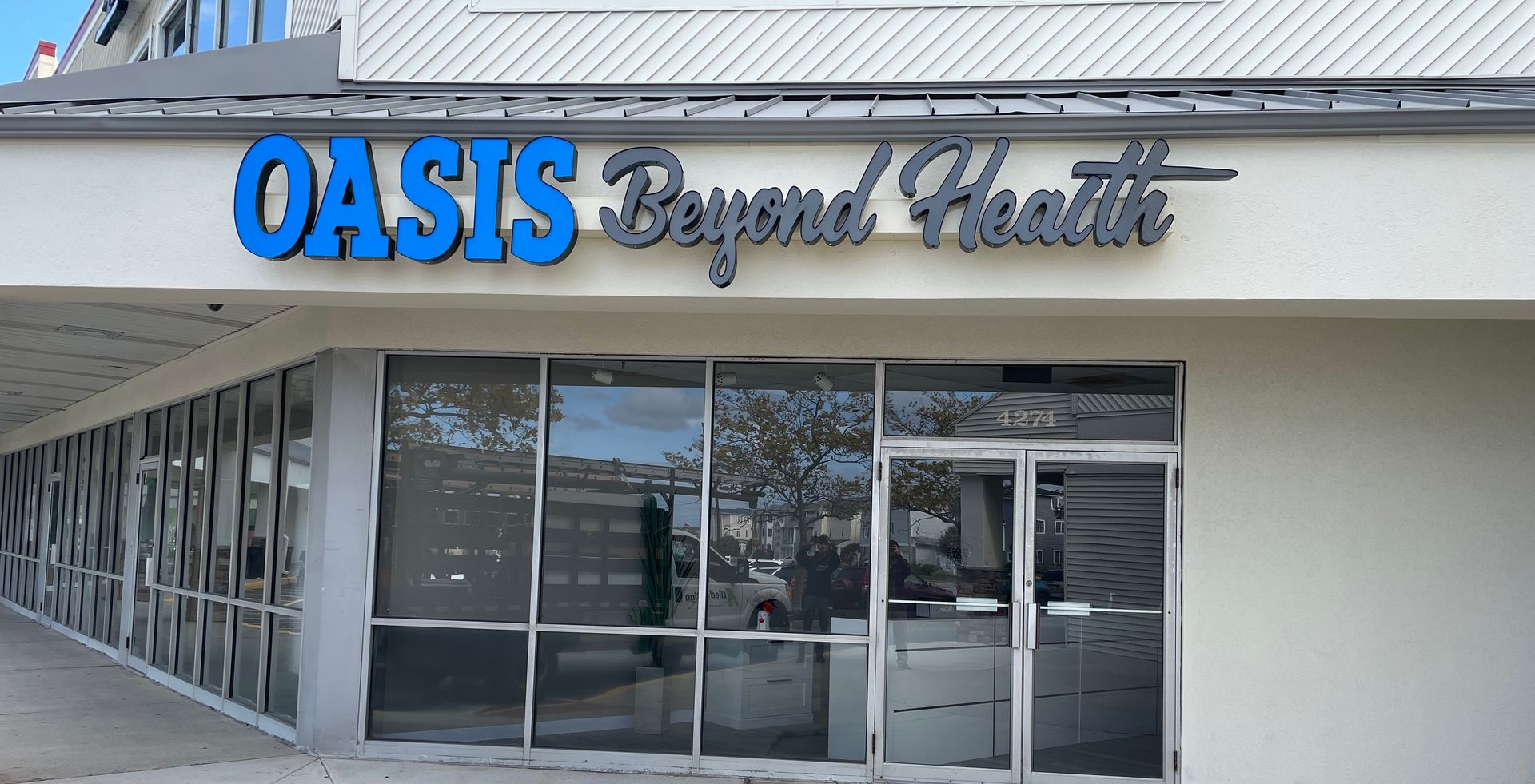 A white building with a blue sign that says oasis beyond health