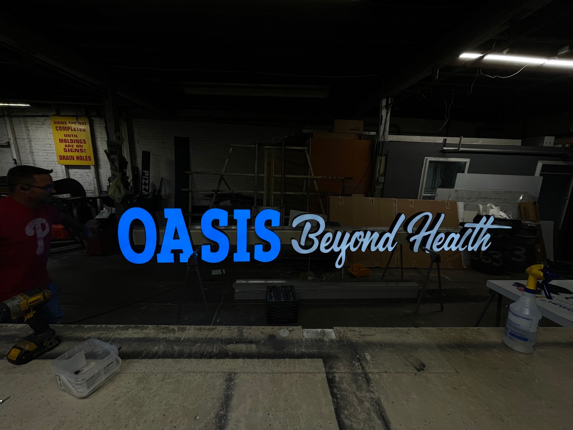 A man is working on a sign that says oasis beyond health.