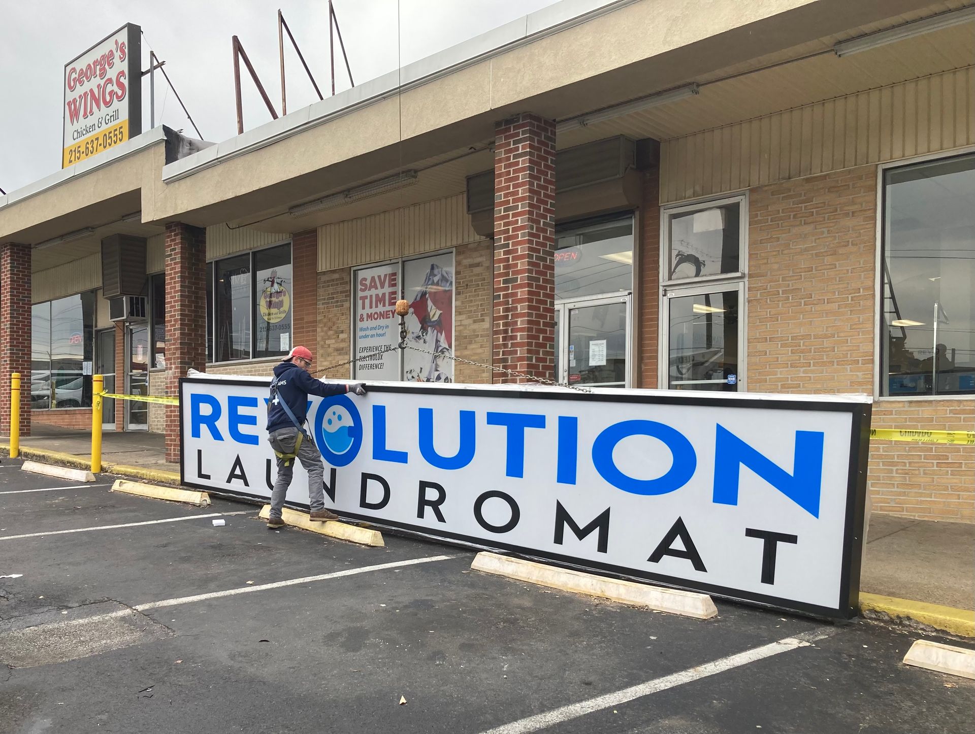A man is standing next to a revolution laundromat sign.