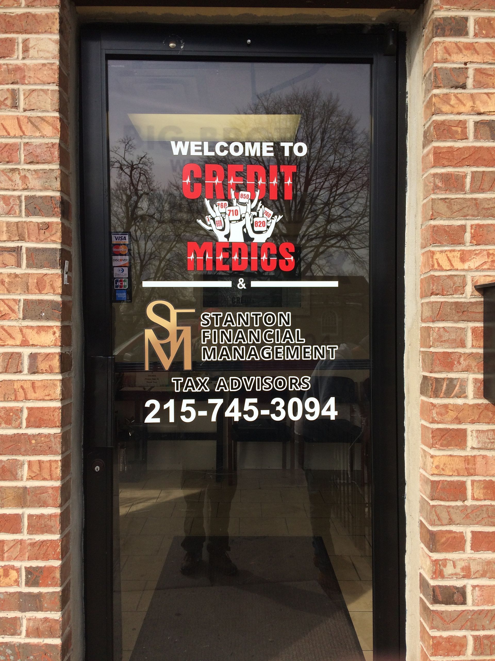 A brick building with a glass door that says welcome to credit medics