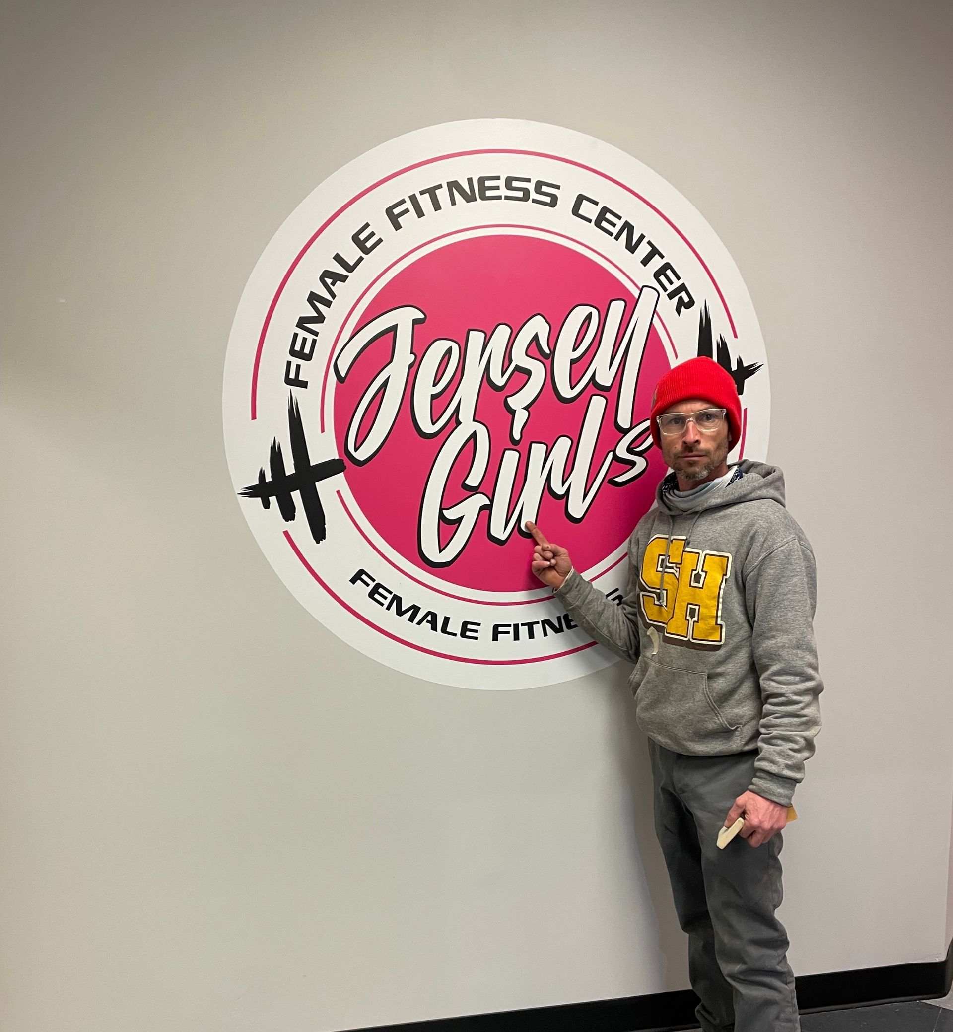 A man is standing in front of a female fitness center logo
