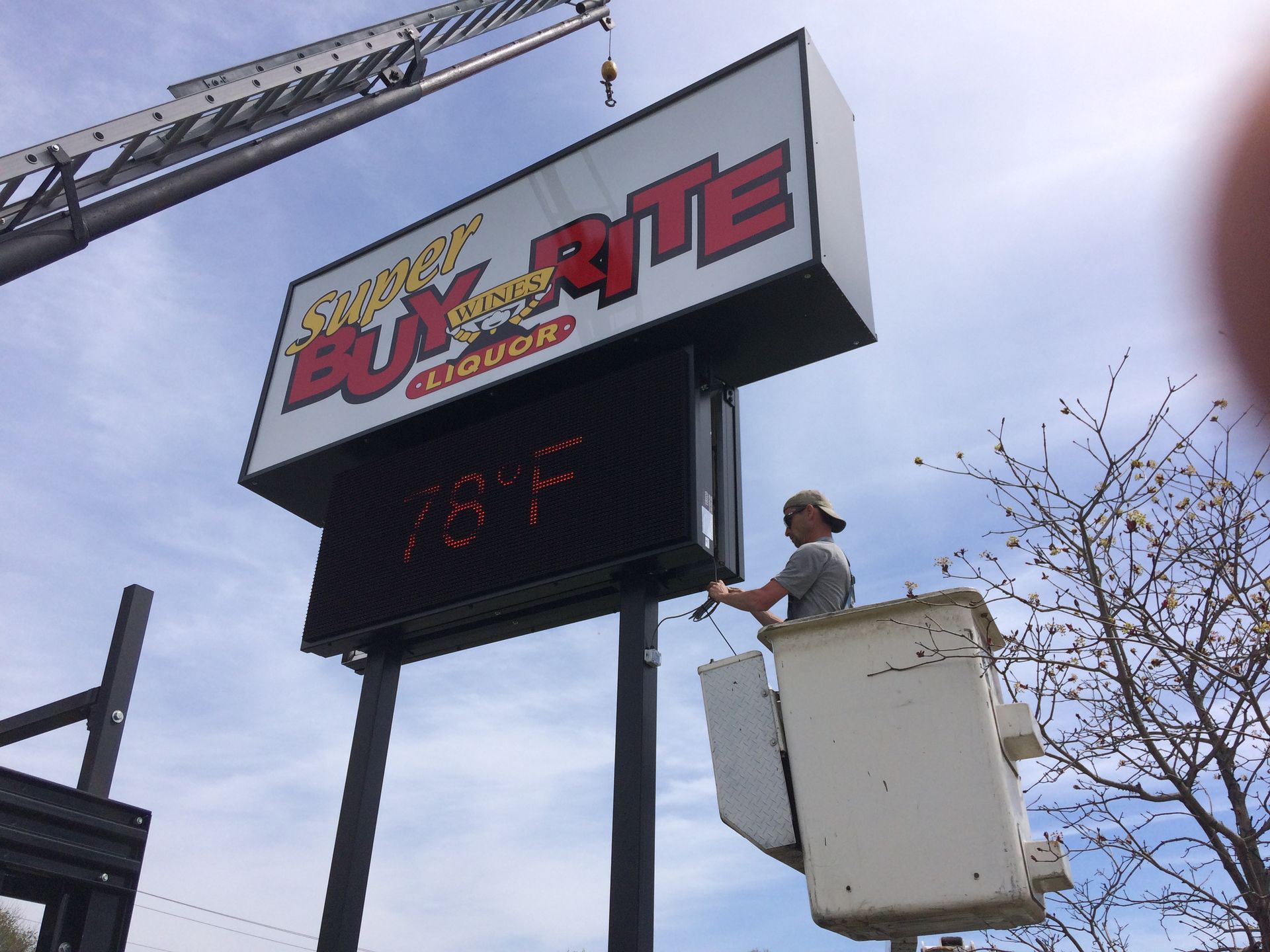 A man is cleaning a sign that says buy rite liquor