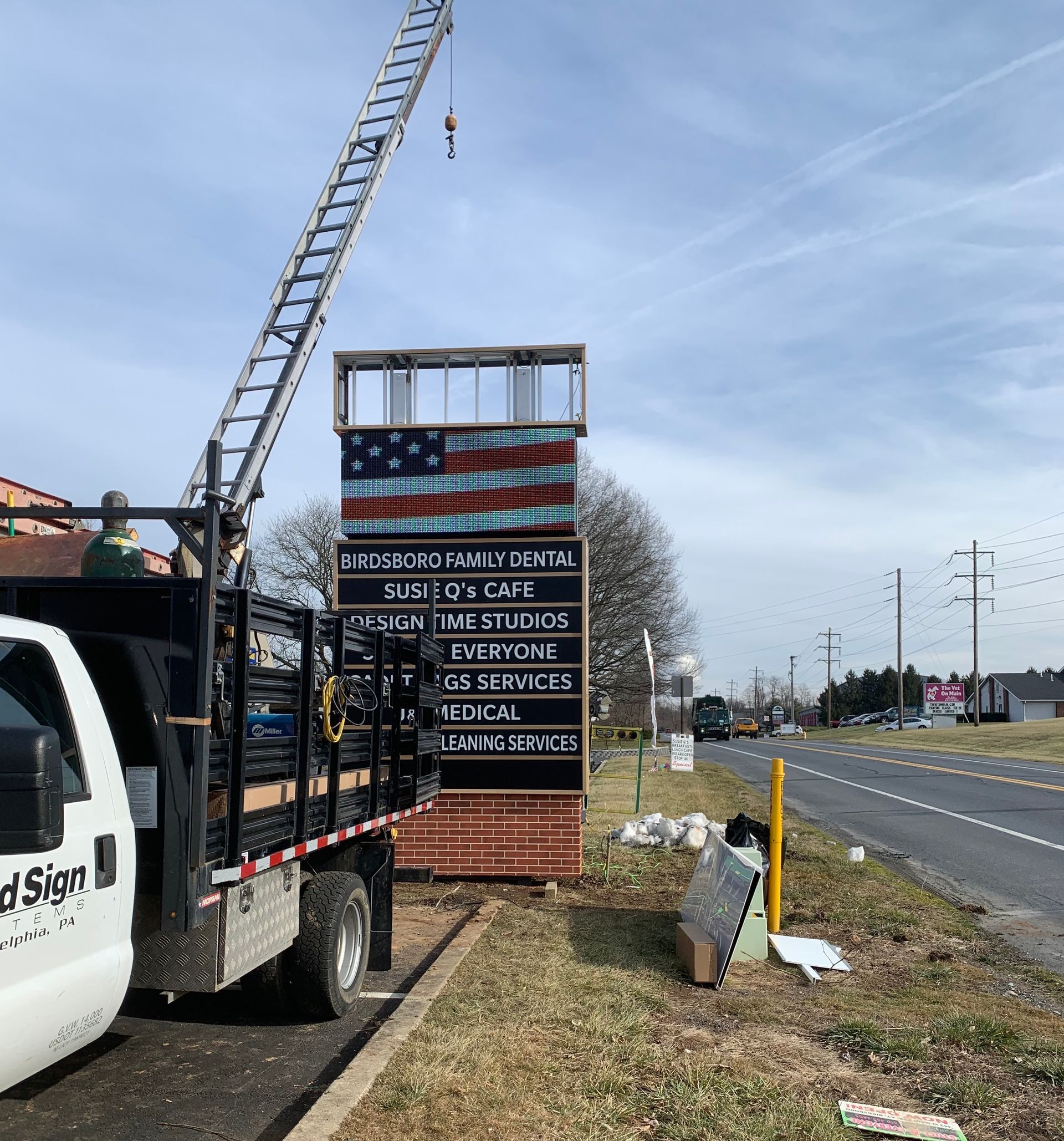 A white truck is parked next to a large sign that says national
