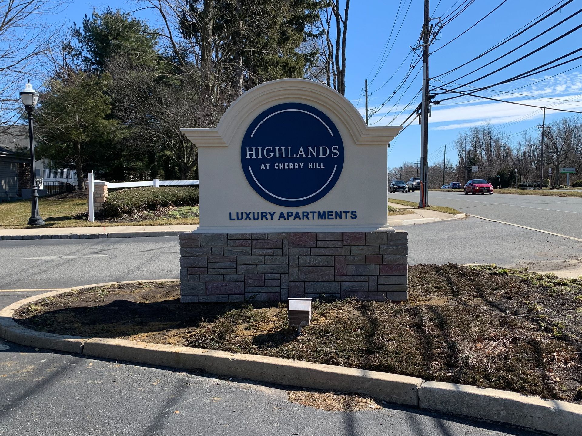 A sign for highlands luxury apartments is in the middle of a parking lot.