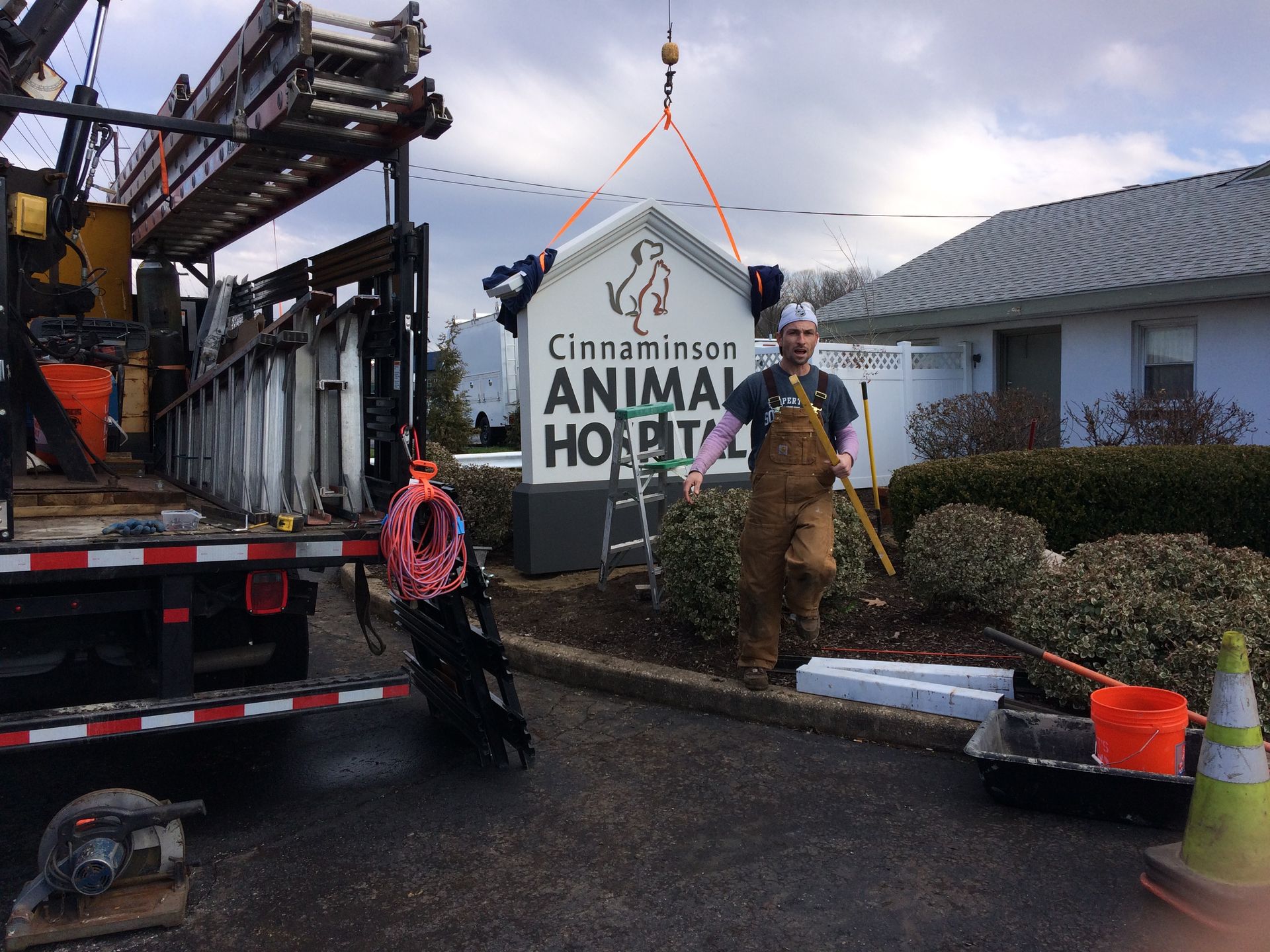 A man is lifting a sign for the cinnamon grove animal hospital.