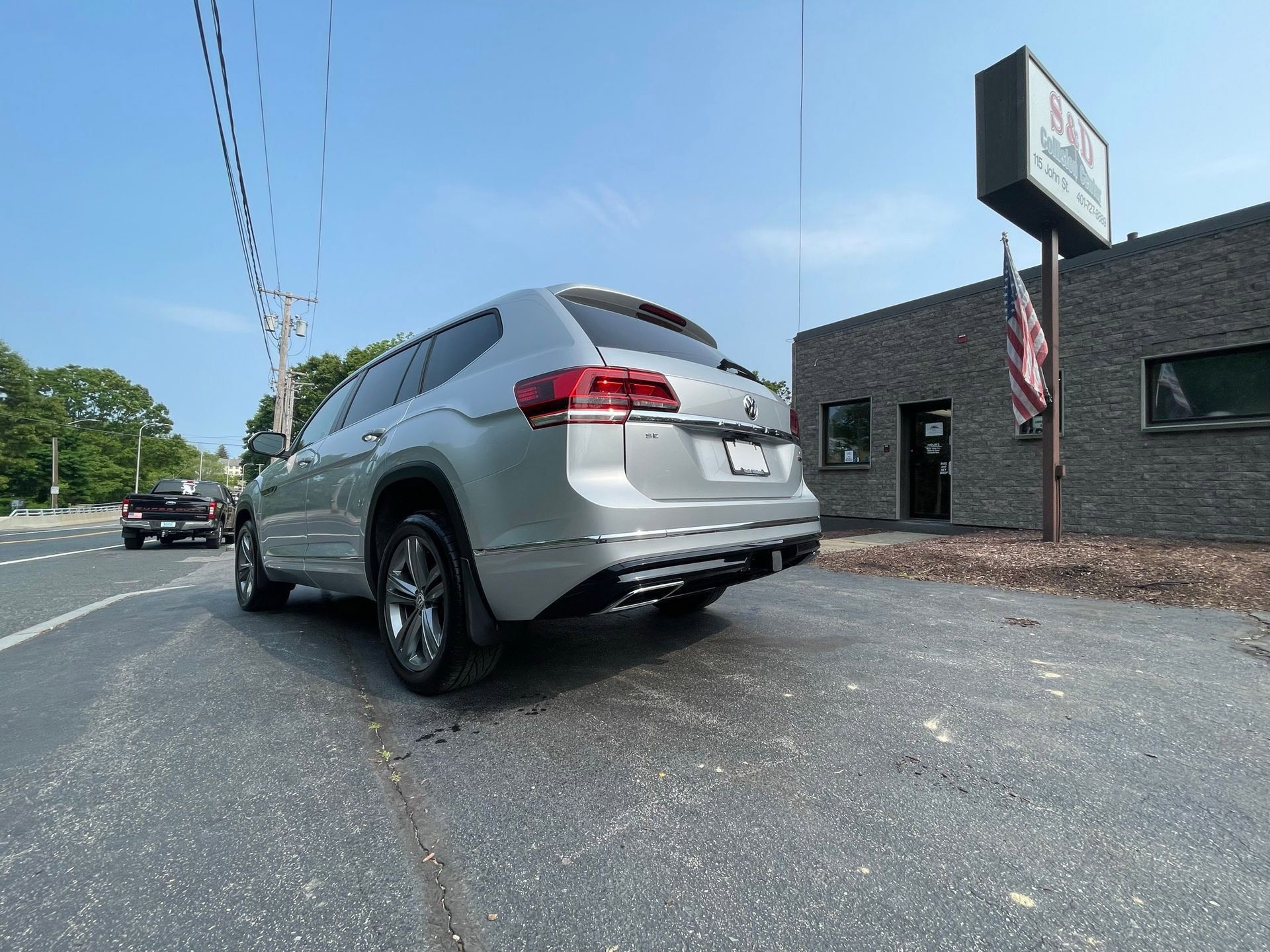 A silver car is parked on the side of the road in front of a building.