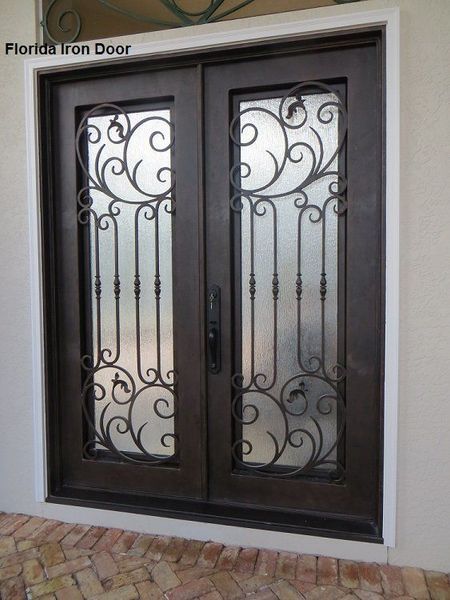 Decorative black metal double front door with frosted glass panels set in a white frame