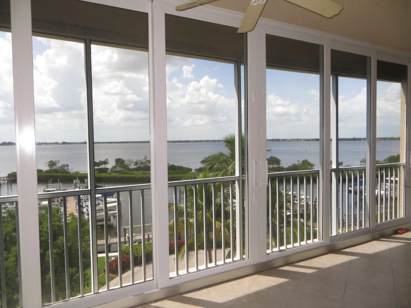 A view from an indoor balcony looking out at a large body of water through floor-to-ceiling glass windows and railings.