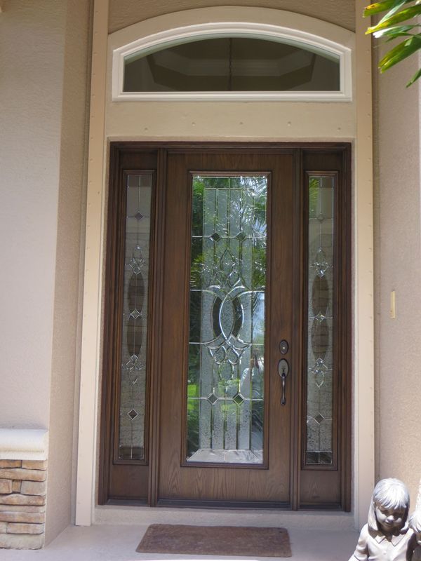 A dark wood front door with glass panels and a decorative arched transom window above.