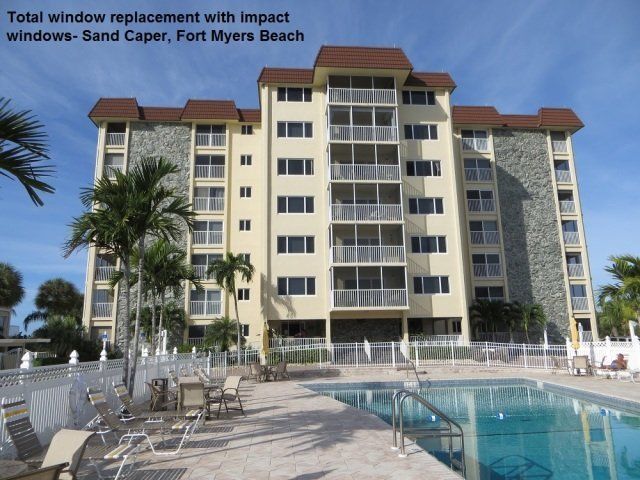 Multi-story Sand Caper condo building with new impact windows, featuring a pool and palm trees in Fort Myers Beach.