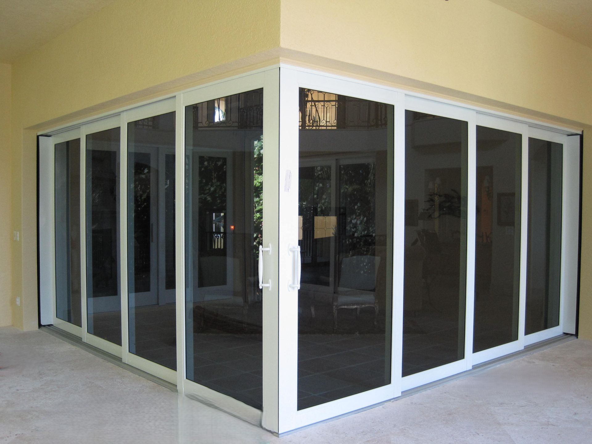 Corner of a modern building with large, white-framed glass sliding doors meeting at a right angle.