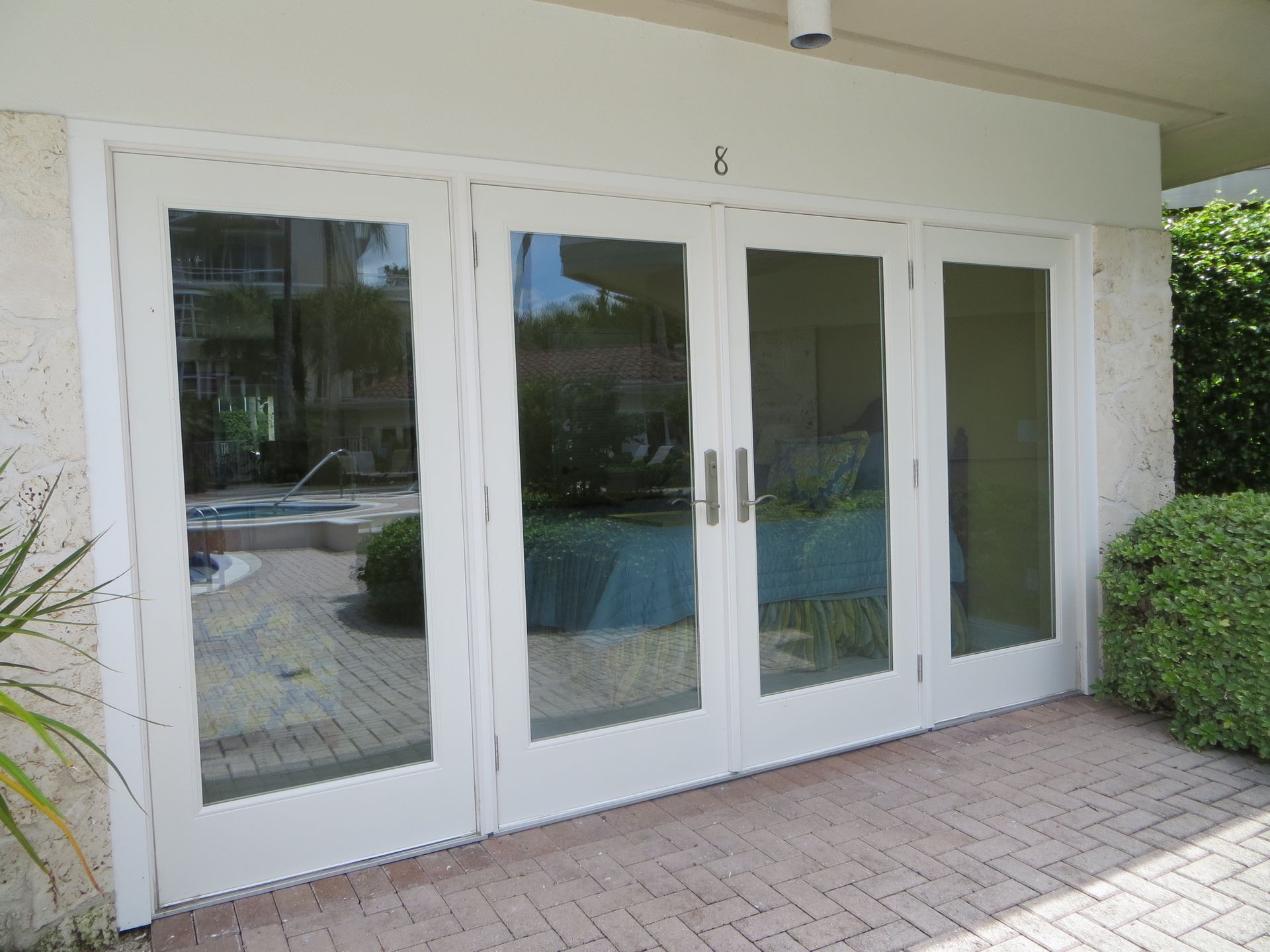 A set of four white-framed glass doors on a patio, with the number 8 visible above the center doors.