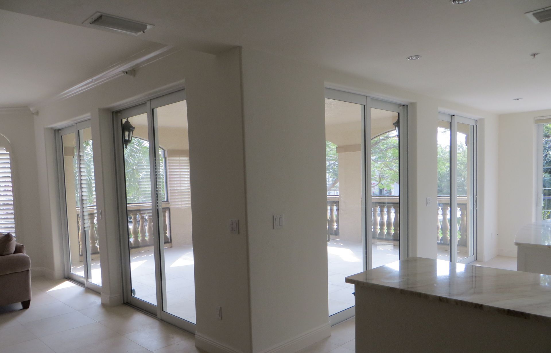 Interior view of a living space with white walls and multiple sliding glass doors opening to a covered balcony.