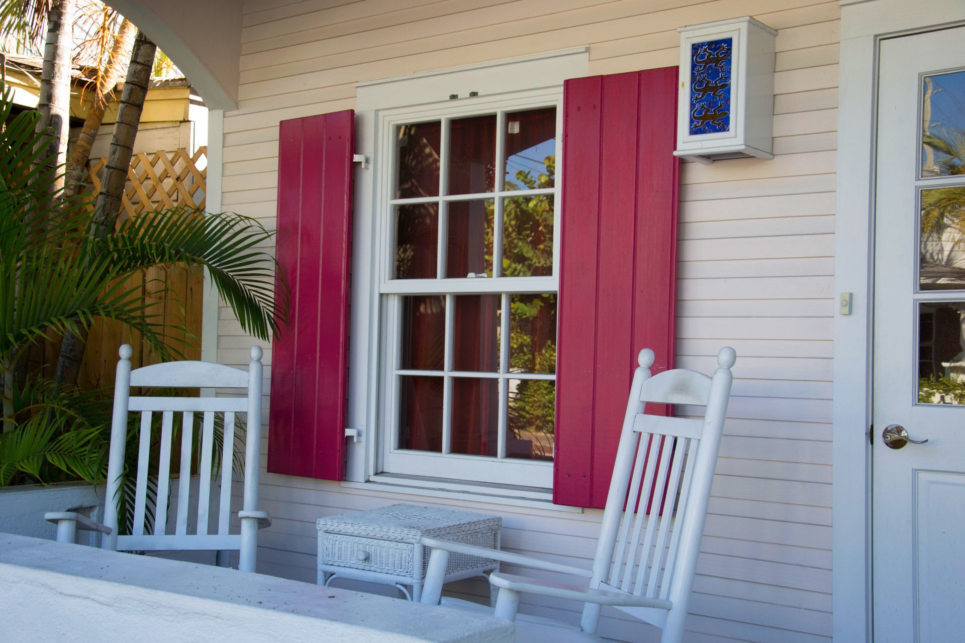 A triple-pane window with white frames and grids, set against cream-colored horizontal siding and dark green trim.