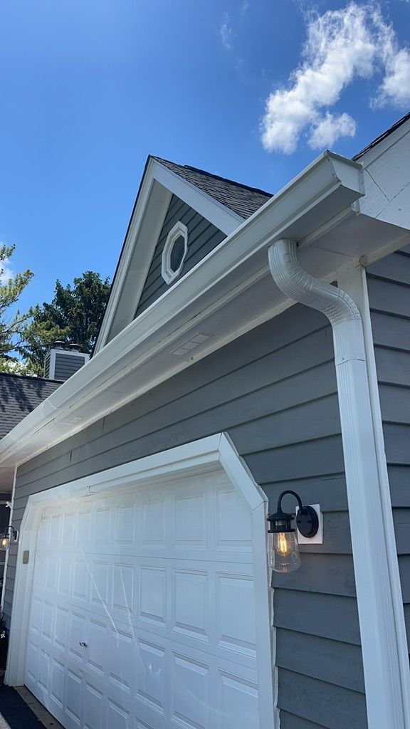A garage with a white door and a gutter on the side of it.