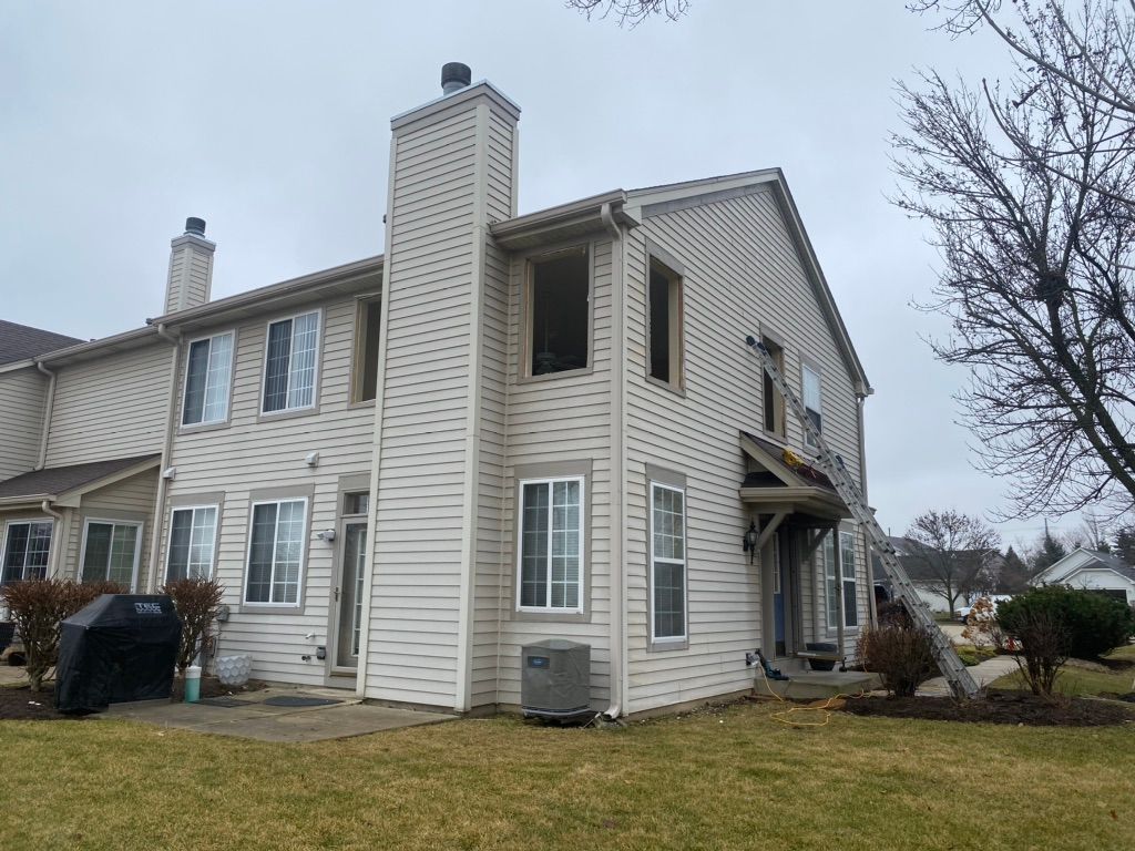 A large white house with a chimney and a lot of windows is sitting on top of a lush green lawn.
