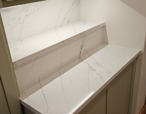 A white counter top with a shelf underneath it in a kitchen.