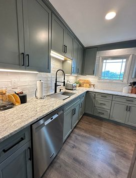 A kitchen with gray cabinets , granite counter tops , and stainless steel appliances.