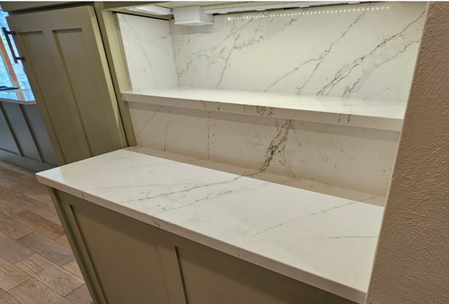 A kitchen with a white counter top and shelves.