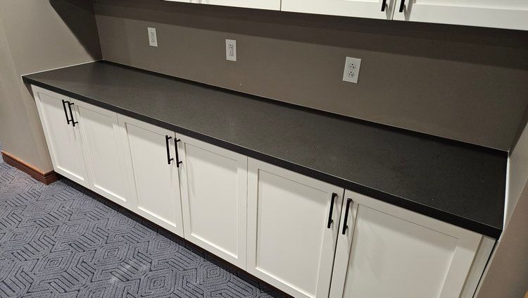 A kitchen with white cabinets and a black counter top.
